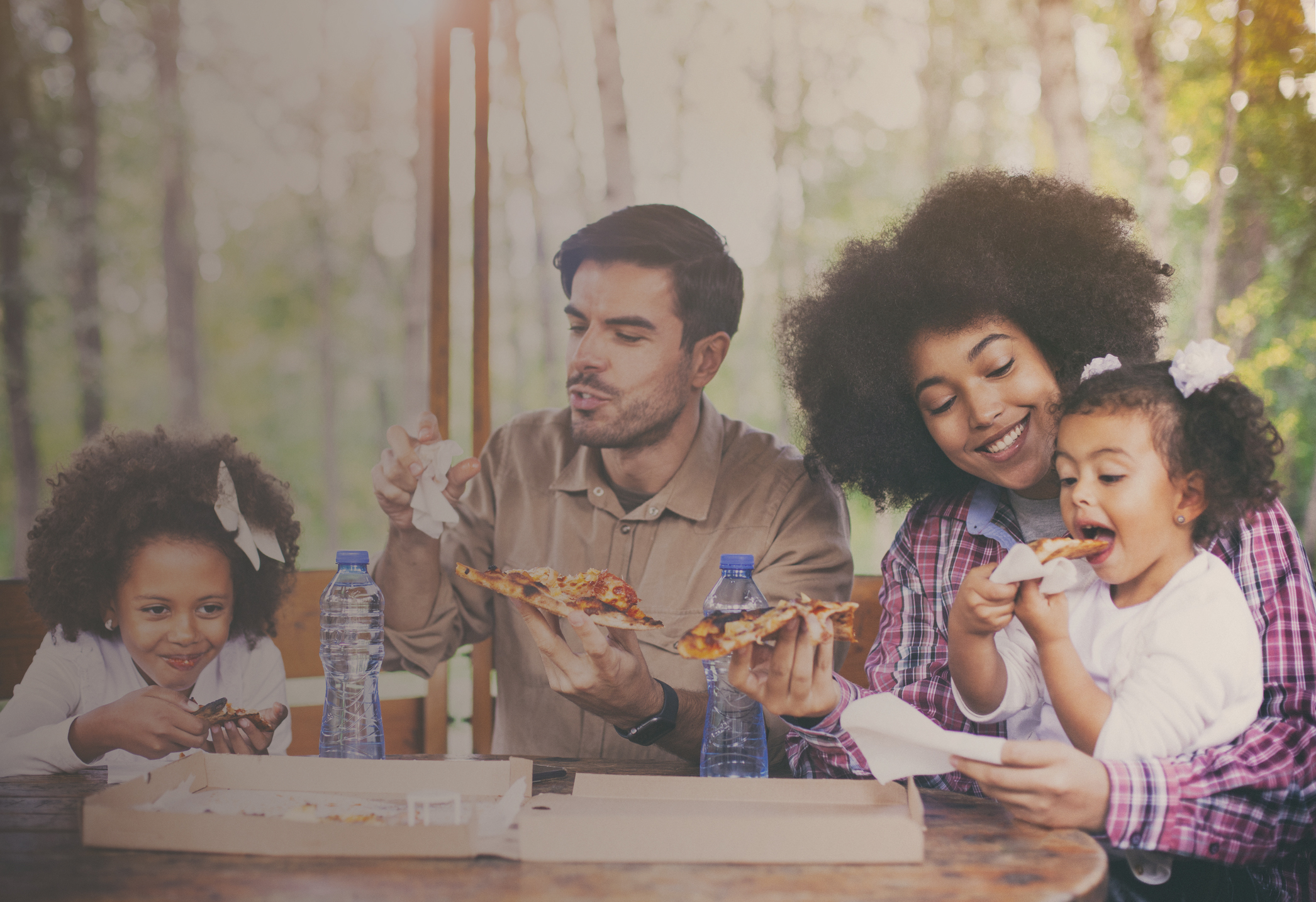 Family eating pizza outdoor together